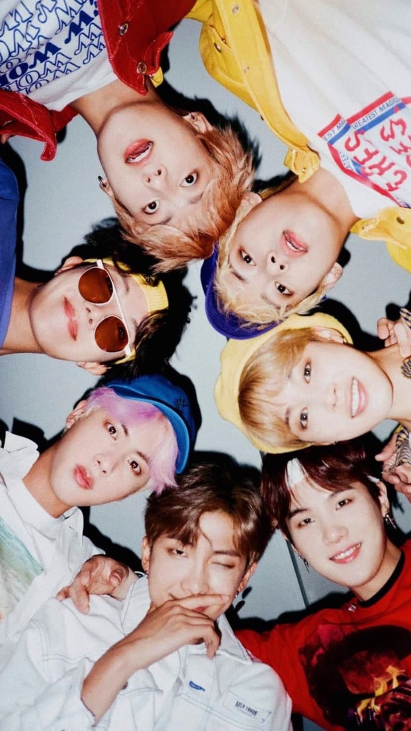 BTS members look down into the camera lens while wearing colorful outfits during their bright Butter music era.