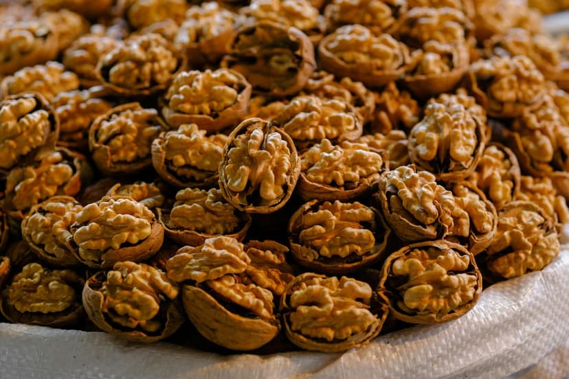 Shelled walnut kernels piled together showing intricate light brown ridges and textures in a macro close-up view.