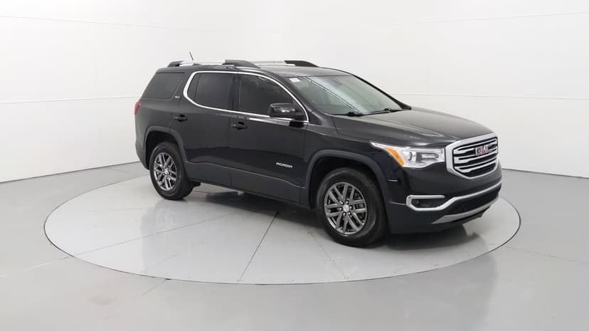 Black GMC Acadia SUV on a white turntable in a bright studio with chrome accents and dark tinted windows.