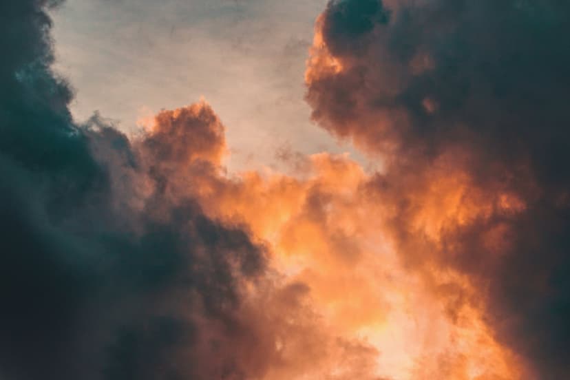 Swirling orange clouds illuminate a dark teal sky during a dramatic sunset, creating a high-contrast nature scene.