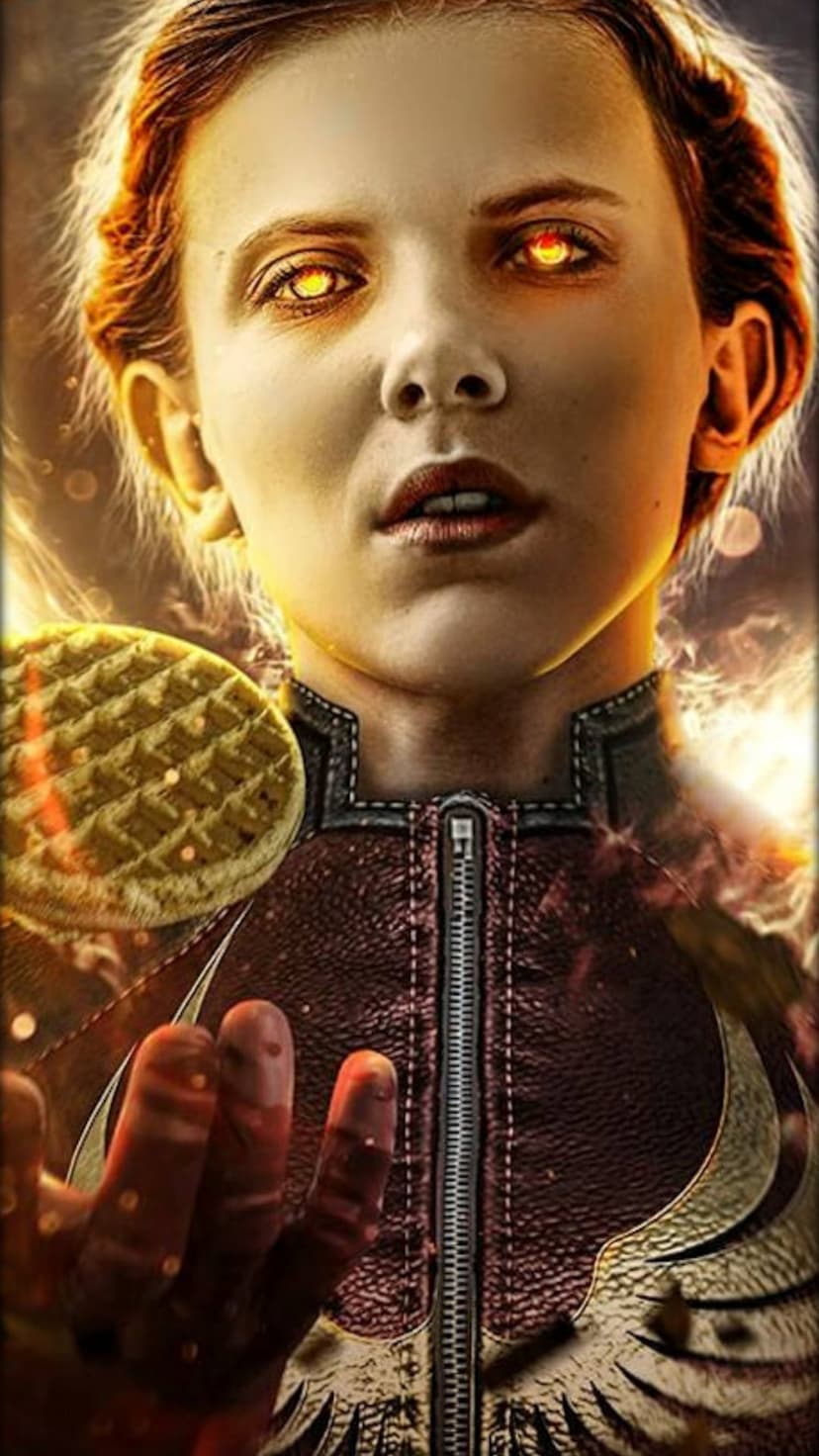 Eleven with glowing yellow eyes holds a waffle while extending her hand amid fiery sparks and smoke.