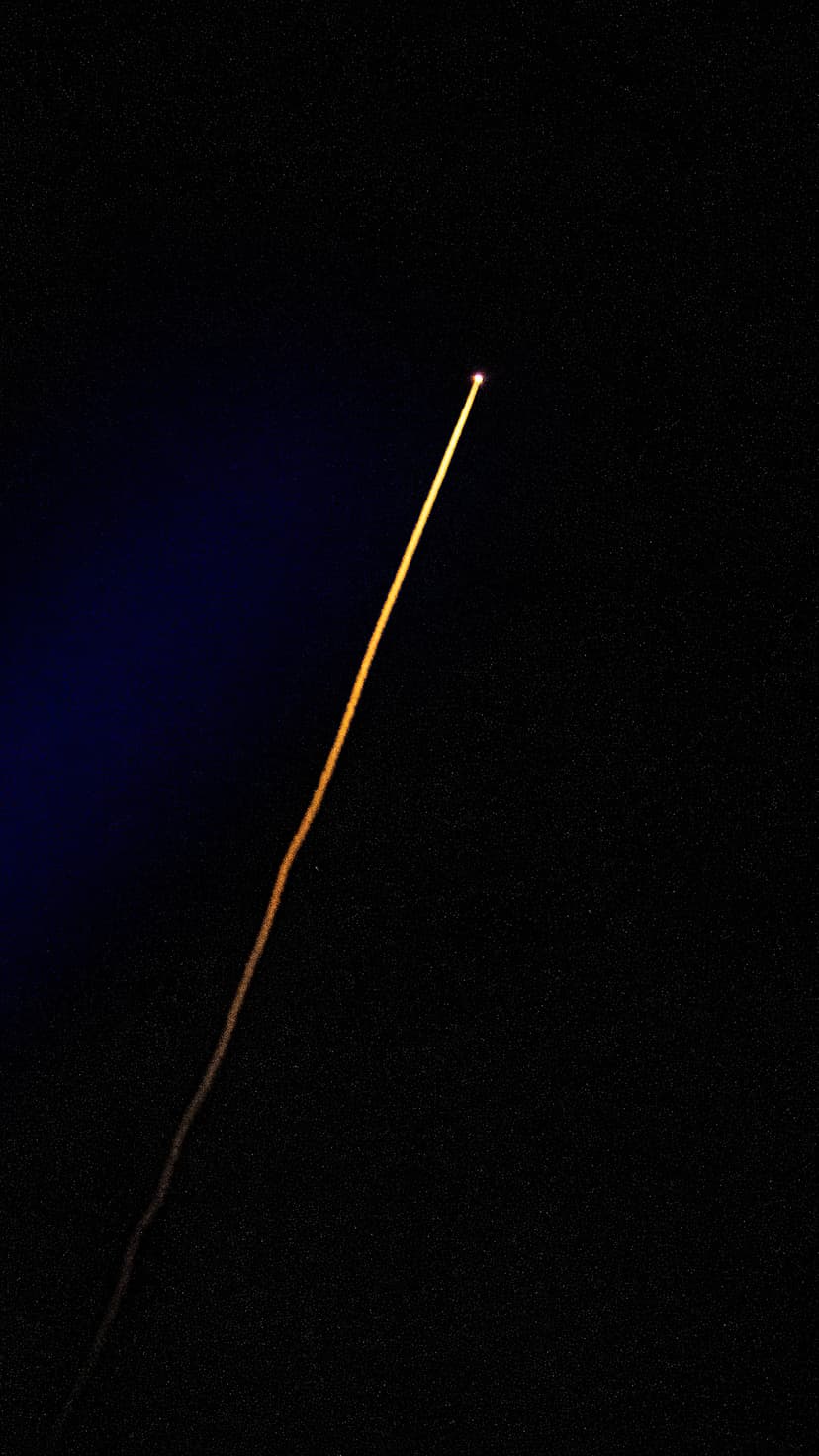 Golden light streak arcs diagonally across a black background with a subtle blue glow in the upper corner.