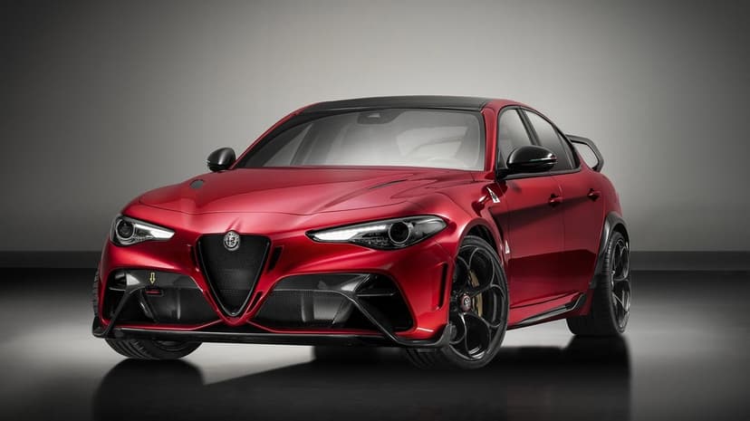 Red Alfa Romeo Giulia GTAm sports sedan with carbon fiber aero and a large rear wing in a dark studio.
