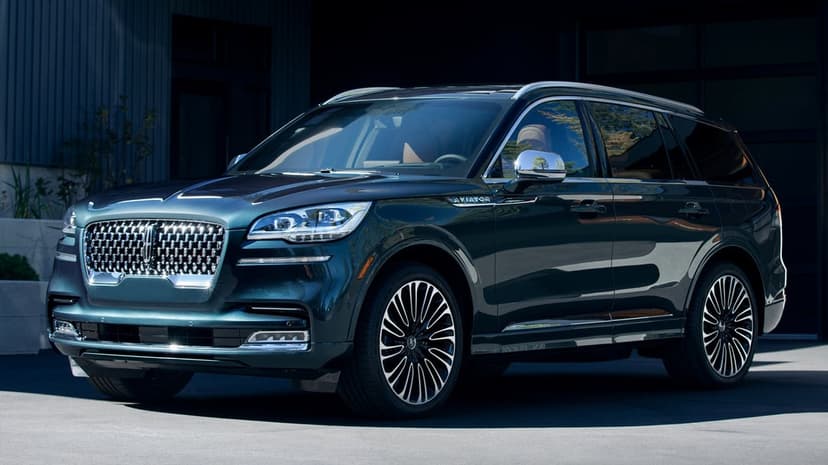 Dark green Lincoln Aviator SUV parked in a modern driveway with chrome accents and multi-spoke wheels.