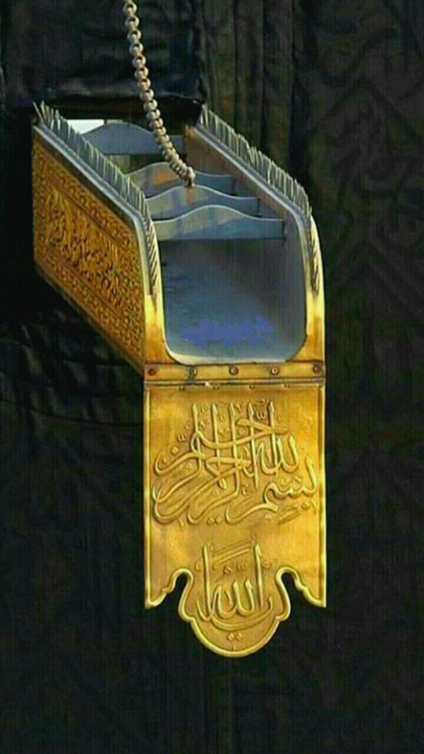 Gold embossed Arabic calligraphy on the black fabric of the Kiswah shows intricate embroidery and metal textures.