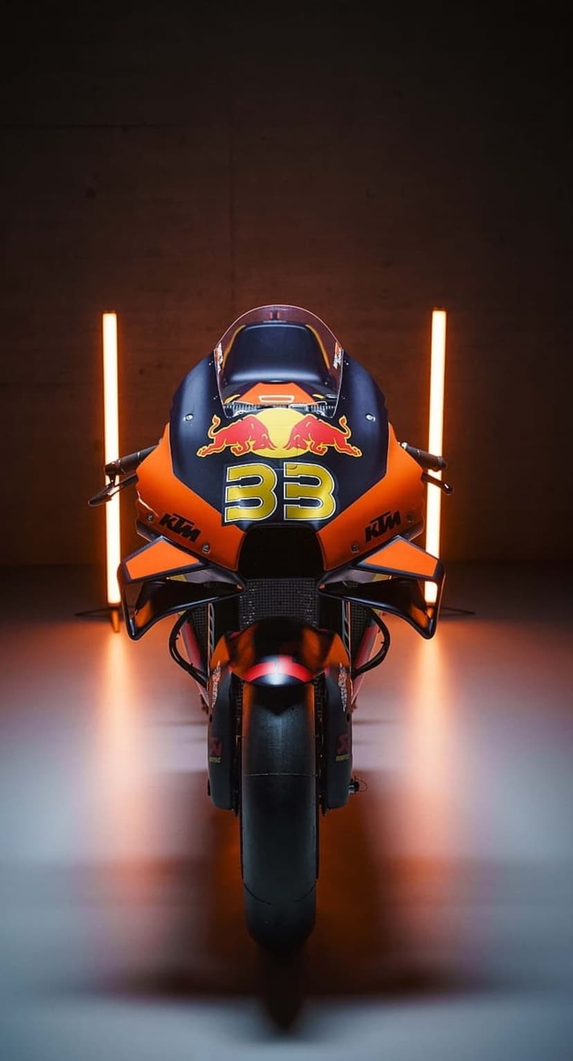KTM RC16 racing motorcycle with number 33 and Red Bull logo centered between vertical orange light tubes.