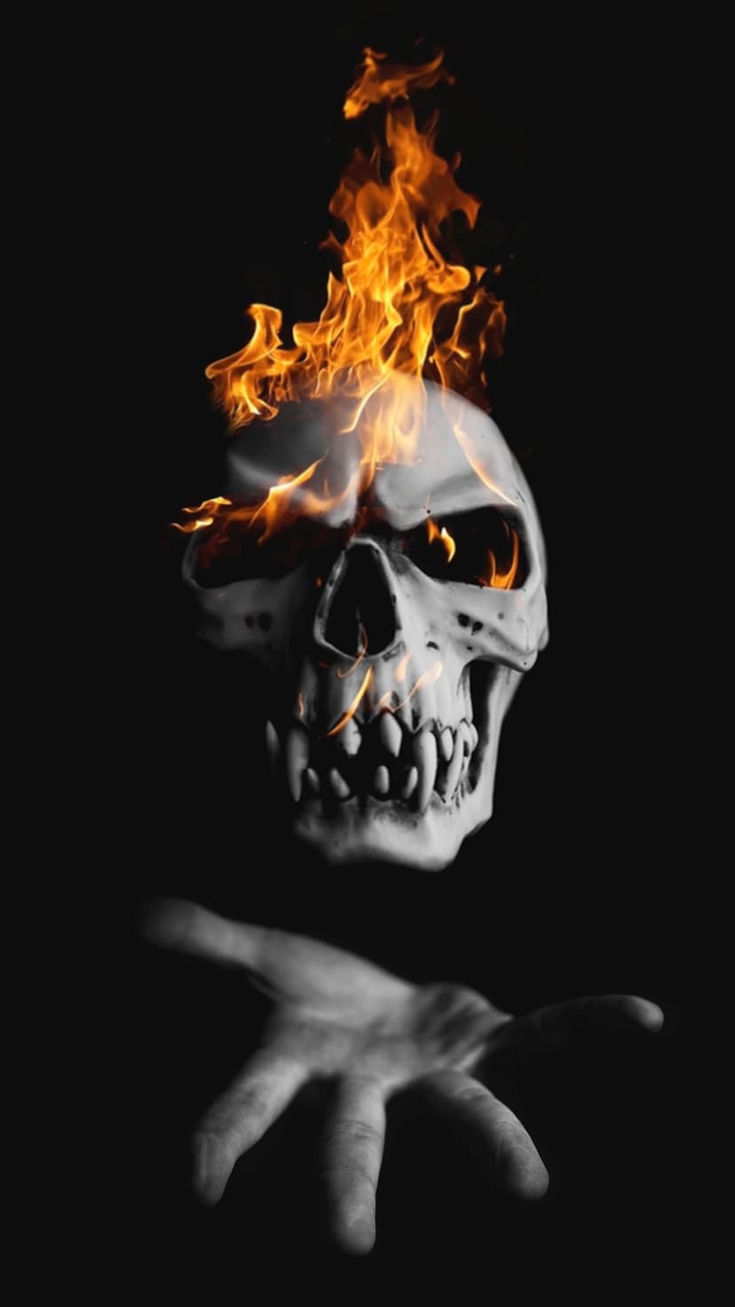 Human skull engulfed in orange fire with a pale hand reaching upwards against a solid black backdrop.