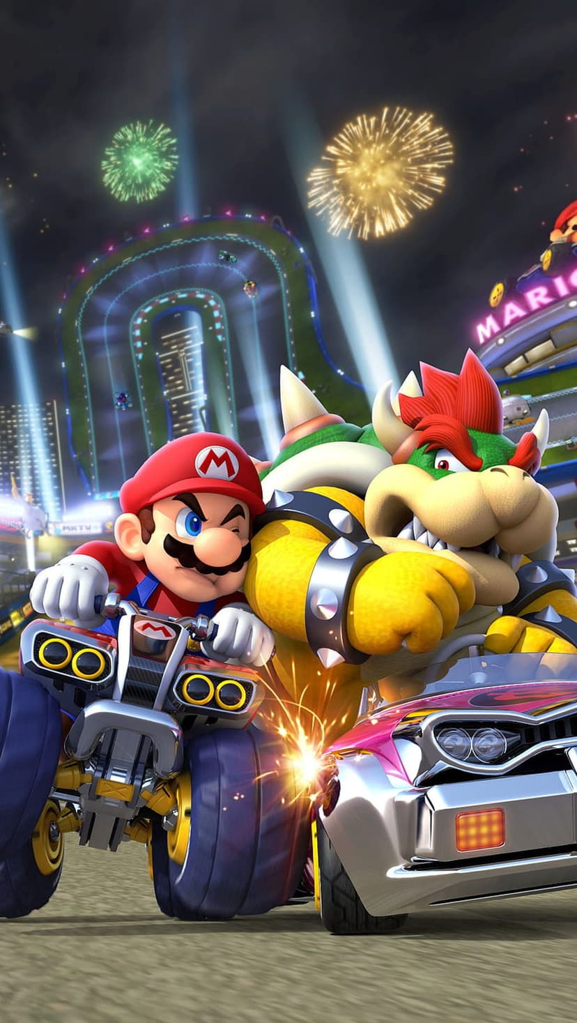 Mario and Bowser race karts at night under exploding fireworks and bright stadium lights with sparks flying.