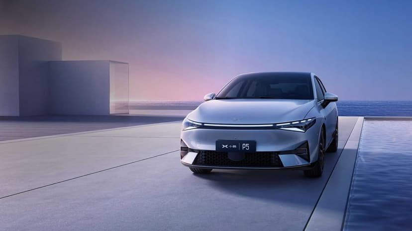 White XPeng P5 electric car on a minimalist concrete patio with a sunset ocean horizon in the background.