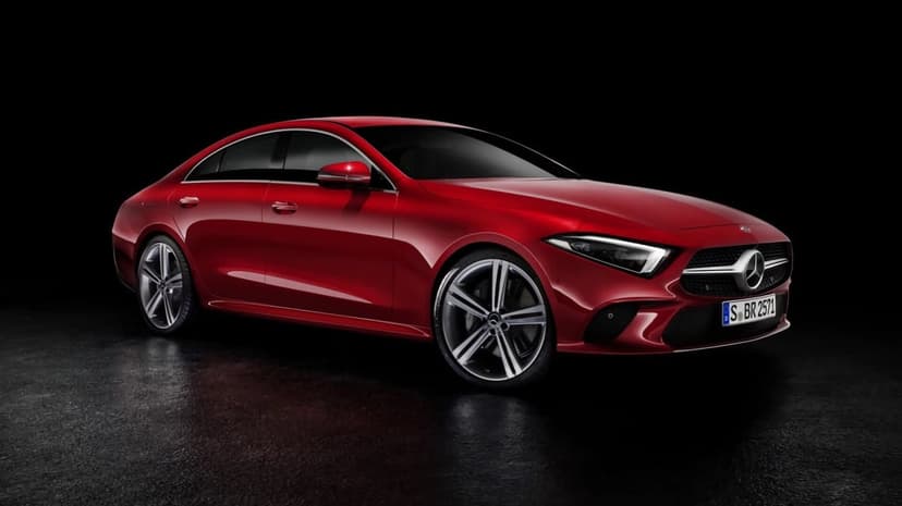 Red Mercedes-Benz CLS luxury car with LED headlights on a dark reflective surface in a minimalist studio.