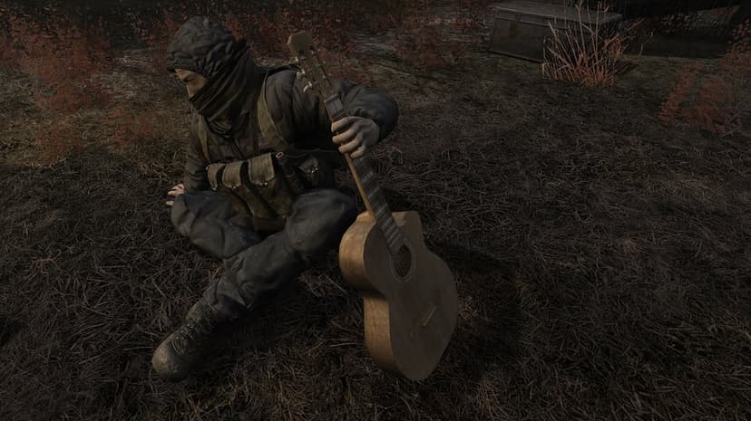 Hooded survivor in tactical gear sitting on dry grass holding an acoustic guitar in a desolate autumn landscape.