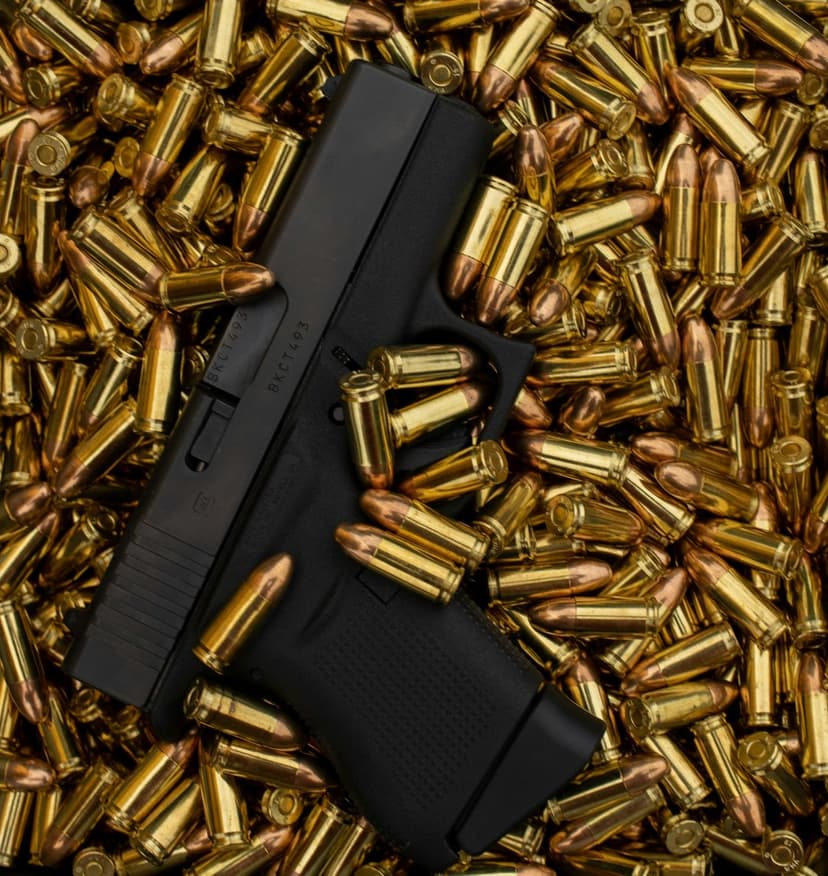 Black semi-automatic pistol resting on a dense pile of metallic brass ammunition rounds and bullet casings.