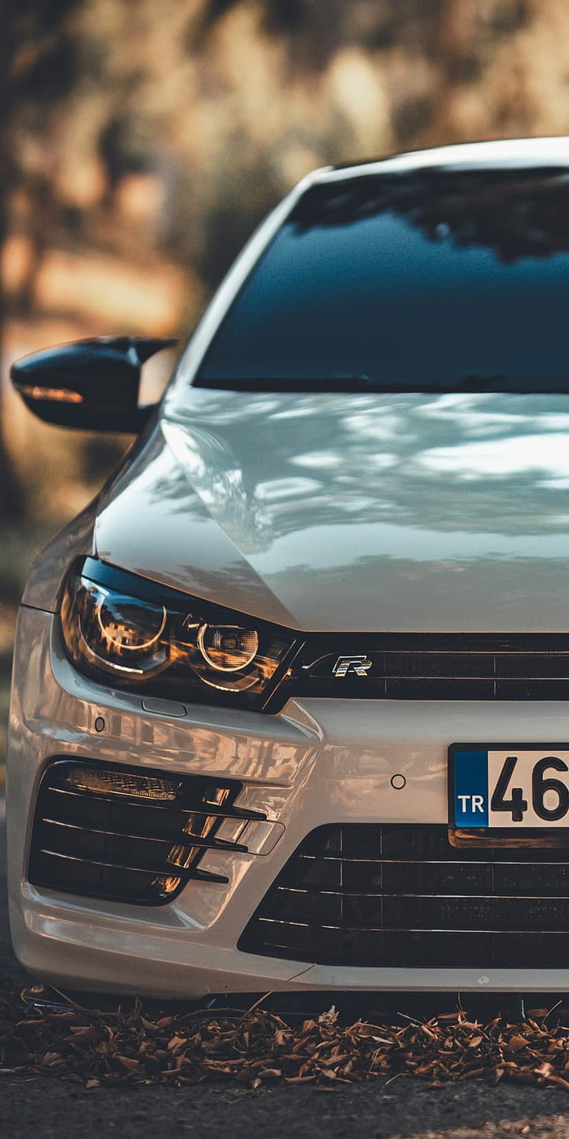 White VW Scirocco R headlight and black honeycomb grille with an R badge under warm natural outdoor light.