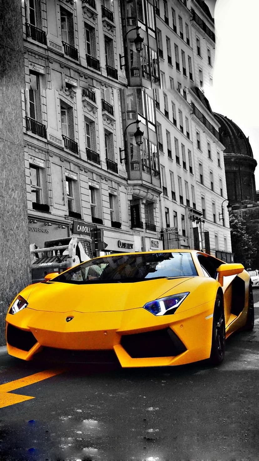 Yellow Lamborghini Aventador parked on a wet cobblestone street in Paris with monochrome buildings in the background.