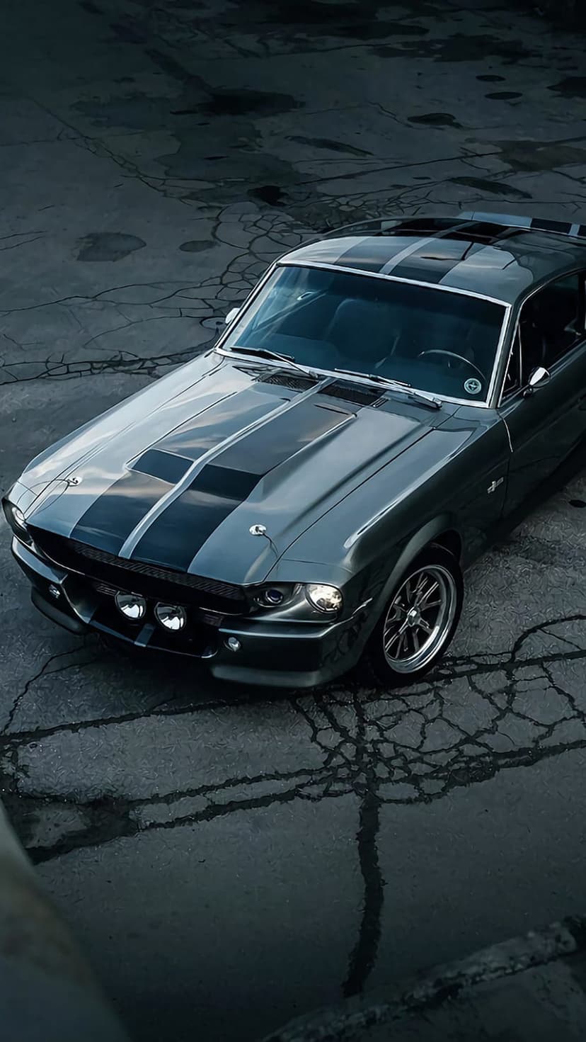 Eleanor Shelby GT500 Mustang with black racing stripes parked on dark cracked asphalt under moody lighting.