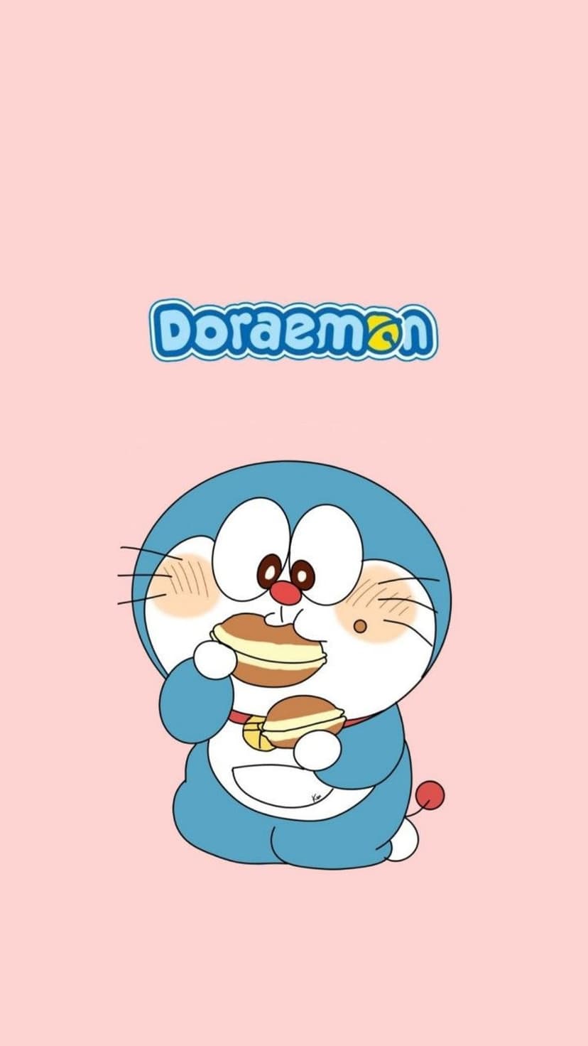 Doraemon the blue robot cat eats two dorayaki pancakes with full cheeks against a soft pastel pink background.