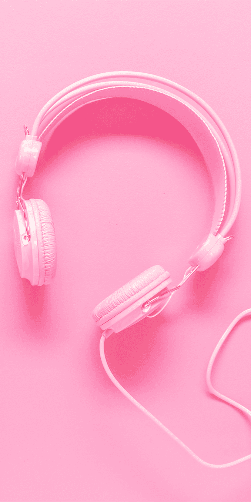 Pink over-ear headphones with a coiled cable on a solid pink surface in a minimalist studio composition.