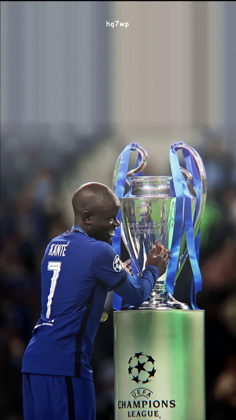 N'Golo Kante lifts the silver Champions League trophy with blue ribbons while wearing a Chelsea jersey.