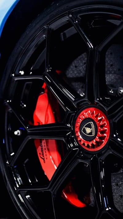 Close-up of a shiny black Lamborghini wheel with red brake calipers