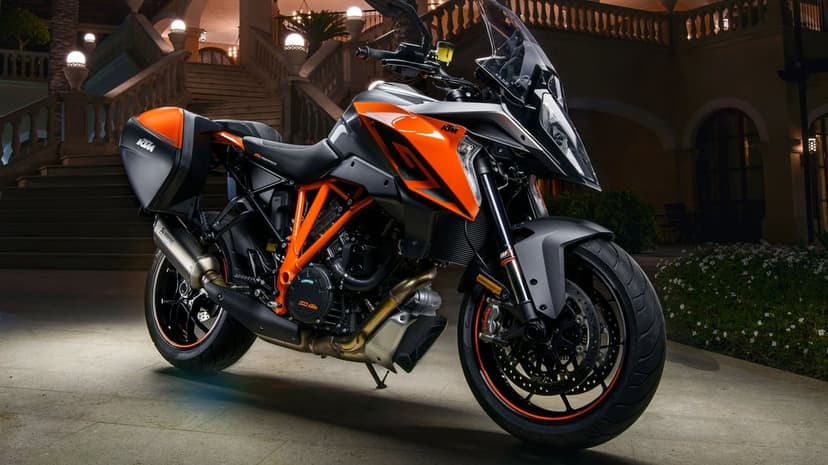 KTM 1290 Super Duke GT motorcycle parked at night on a stone patio with architectural stairs and warm lighting.