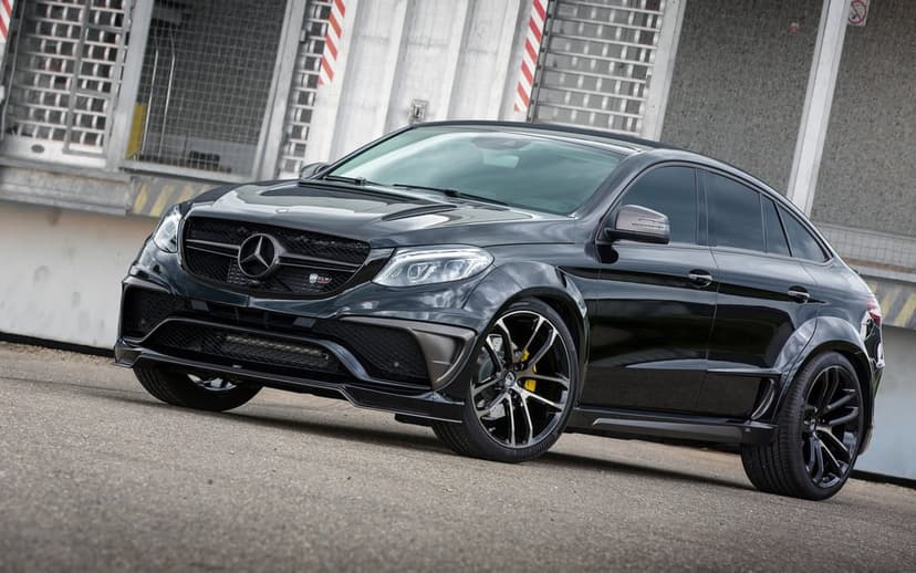 Black Mercedes-Benz GLE Coupe with widebody kit and yellow calipers parked in an industrial setting.