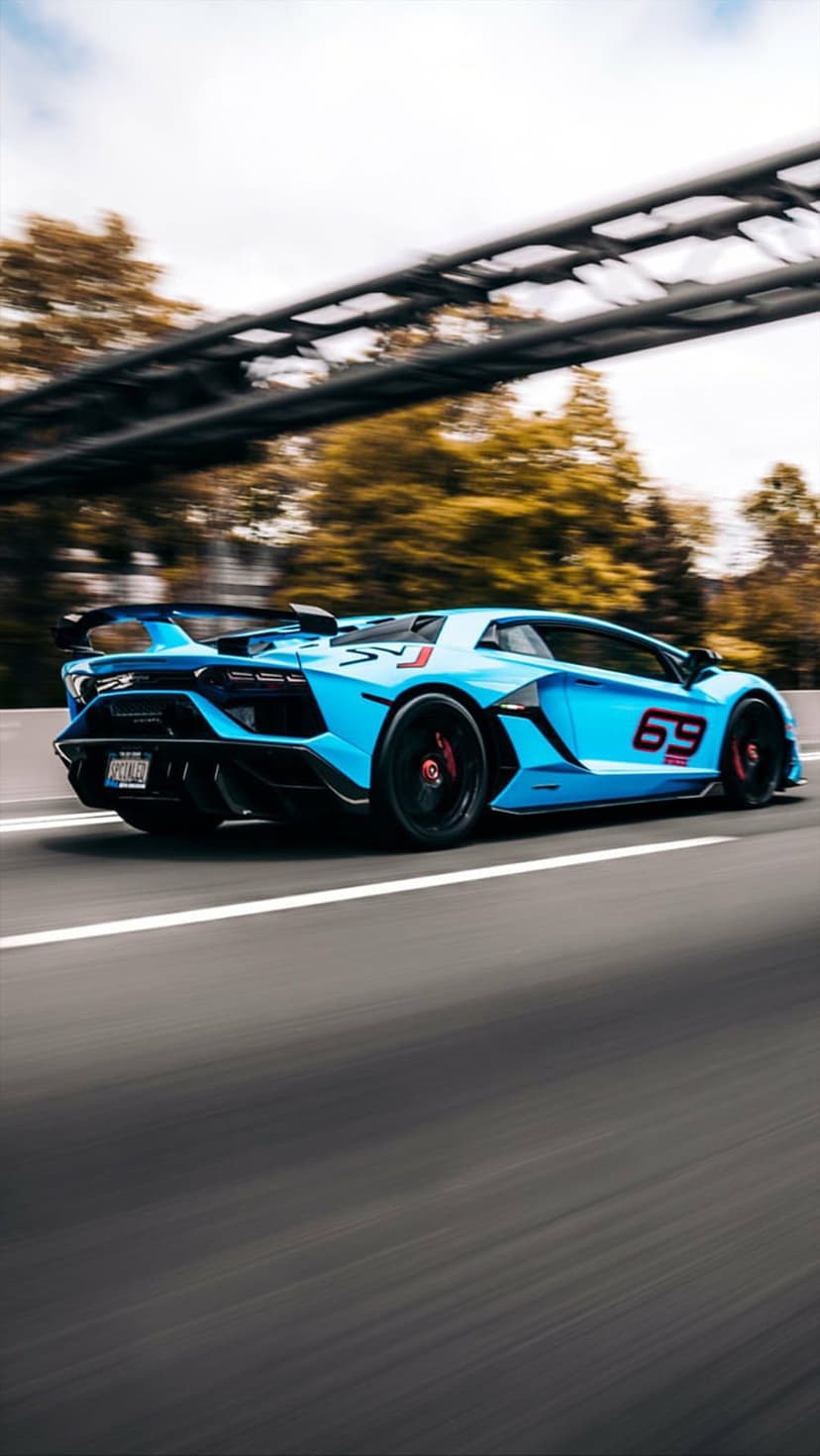 Blue Lamborghini Aventador SVJ with number 69 racing on a highway past autumn trees and a concrete overpass.
