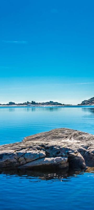 Calm Blue Waters Meet Rocky Shoreline Under Clear Sky