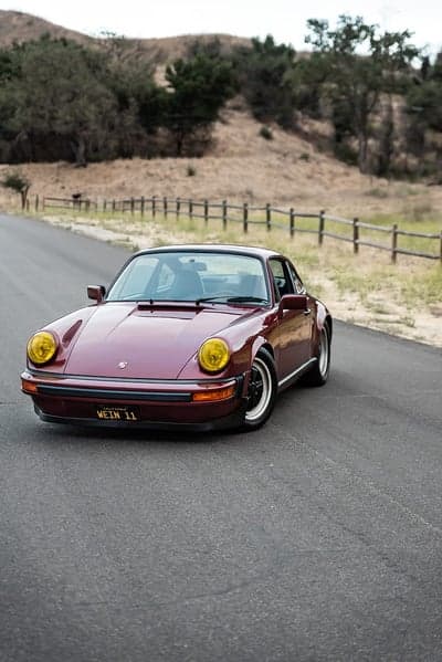 Maroon Porsche 911 parked on a rural road