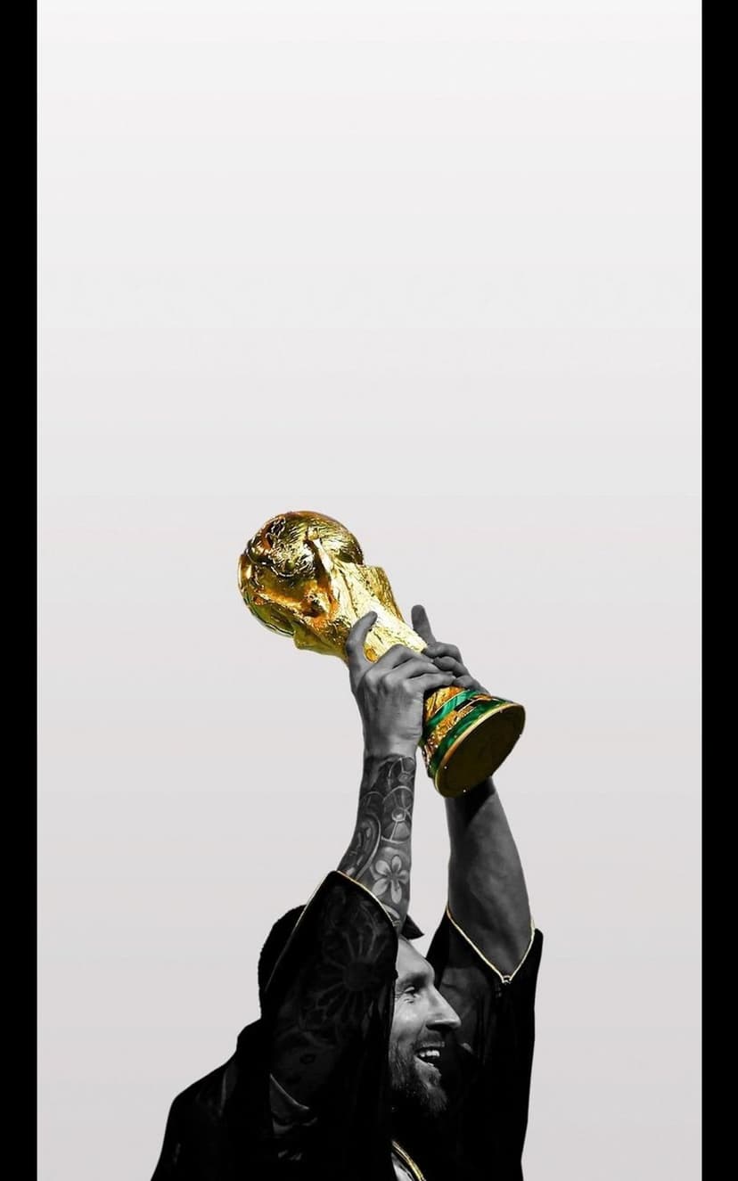 Lionel Messi holds the gold World Cup trophy high against a minimalist grey background showing arm tattoos.