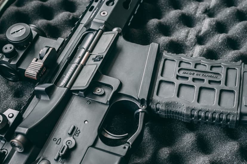 Black AR-15 rifle receiver and magazine with tactical sight on textured dark foam padding in a storage case.