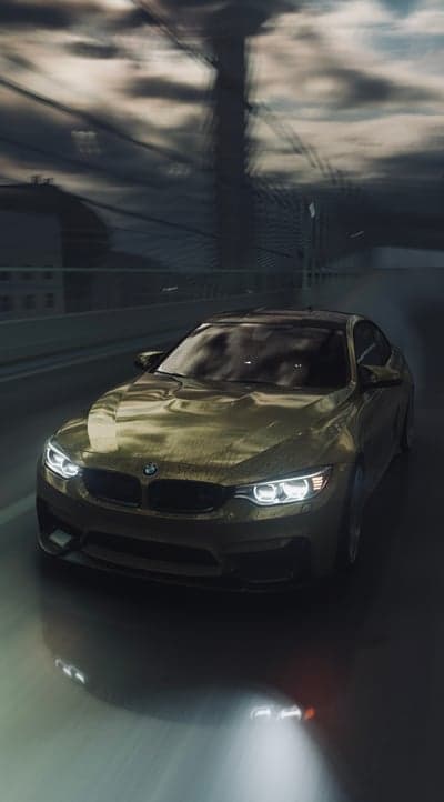 Golden BMW M4 Driving Through Moody Urban Landscape