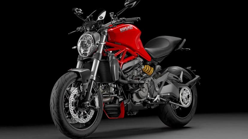 Red Ducati Monster motorcycle with exposed mechanical parts and black background in a studio setting.