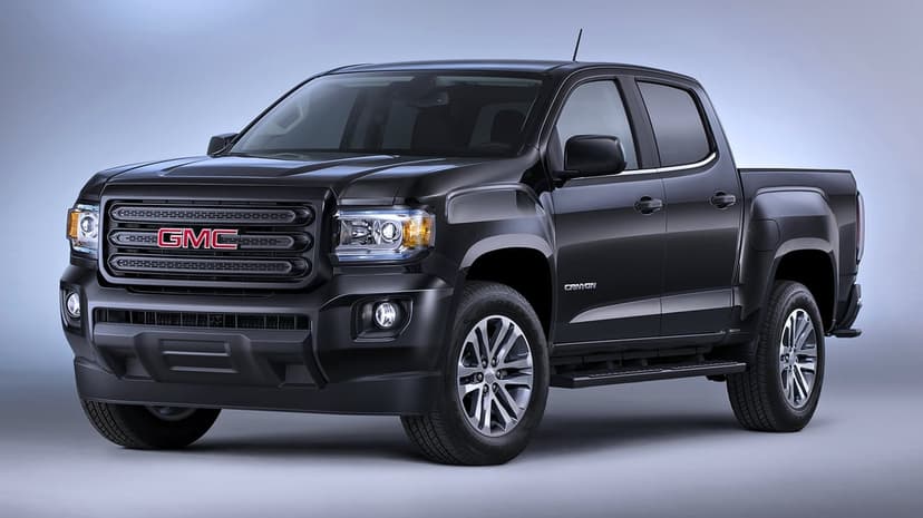 Black GMC Canyon pickup truck with a blacked-out grille and alloy wheels in a clean studio environment.