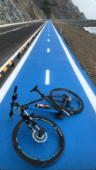 Blue coastal bike path with mountain backdrop