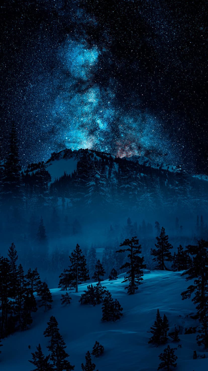 Snow-covered mountain ridges stand beneath a vibrant Milky Way galaxy and a dense field of glowing stars.