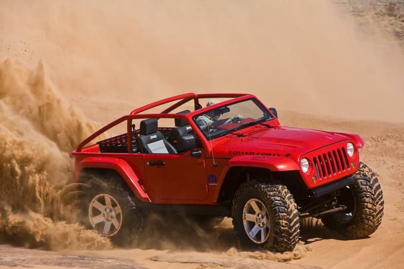 Red Jeep Wrangler Lower Forty concept driving through desert sand dunes with a large dust trail and red roll cage.
