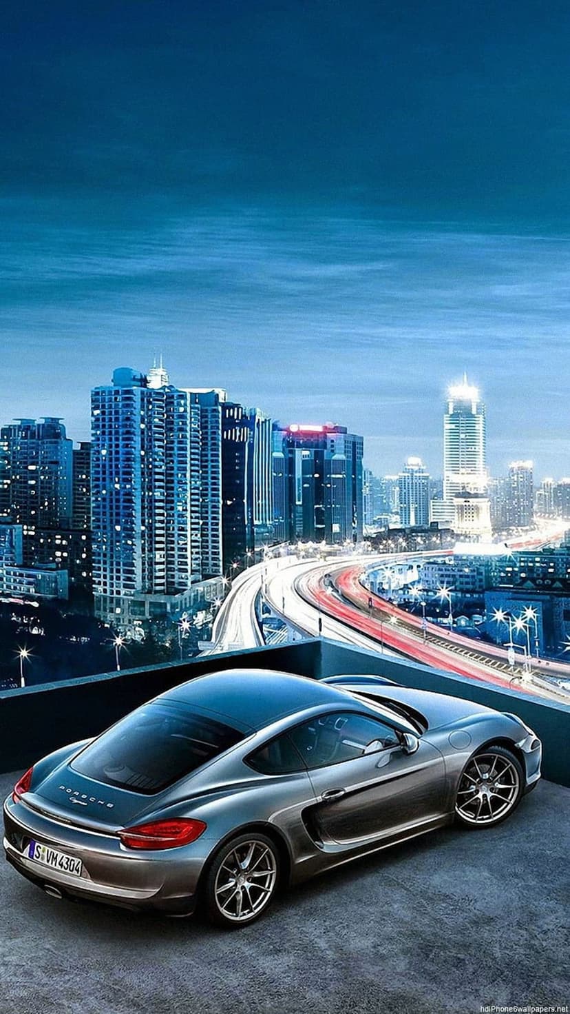 Porsche sports car on a rooftop overlooking a glowing city at dusk with skyscrapers and highway lights.
