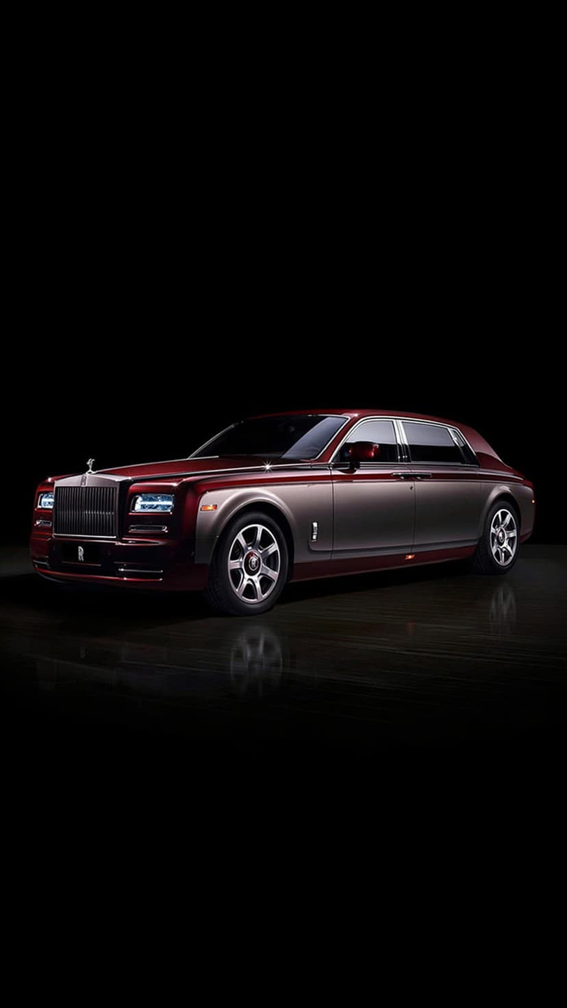 Rolls-Royce Phantom sedan with red and silver paint, chrome grille, and alloy wheels in a dark luxury showroom.