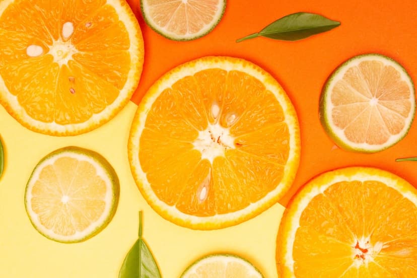 Orange and lime slices arranged on a two-tone yellow and orange surface with detailed pulp textures.