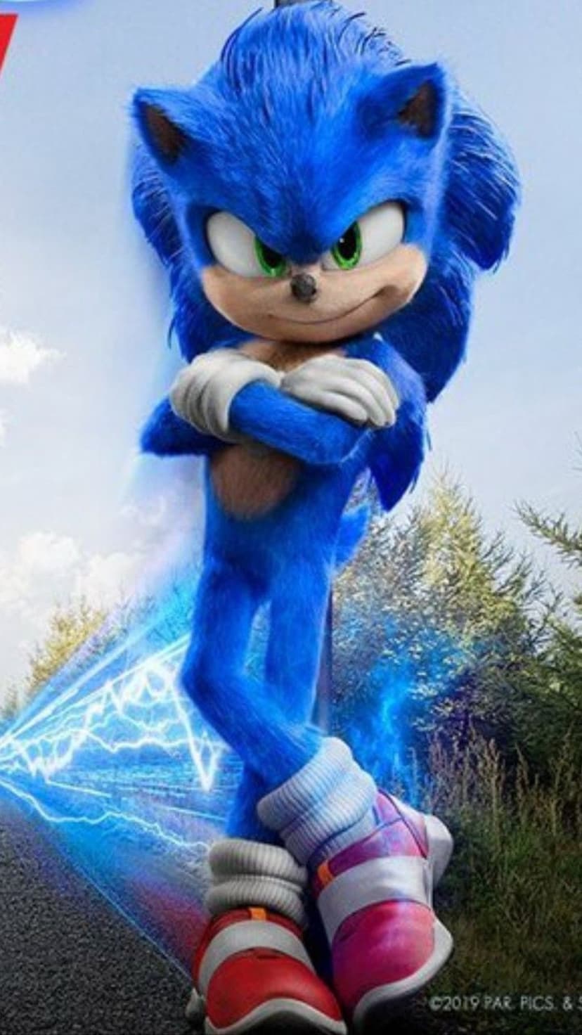Sonic the Hedgehog with crossed arms stands amidst blue electricity on a blurred asphalt road near green trees.