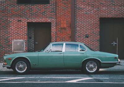 Retro Green Jaguar Sedan Against Red Brick Phone Background