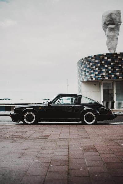 Black Porsche Targa parked on cobblestone street