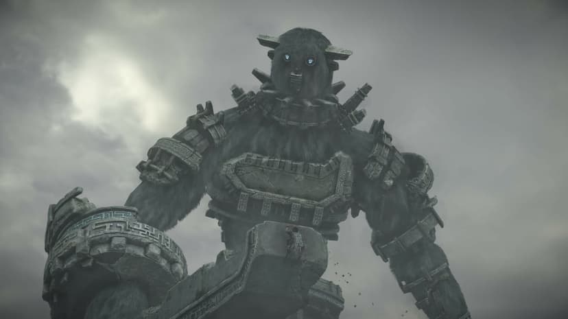 Giant stone colossus with glowing blue eyes towers over a small climber against a foggy grey sky.