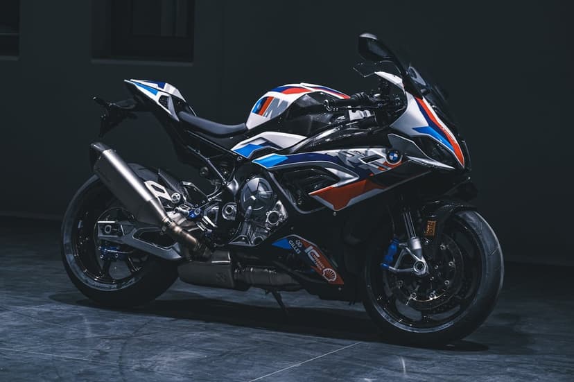 BMW M 1000 RR motorcycle with M livery and carbon fiber parts in a dark studio with dramatic lighting.
