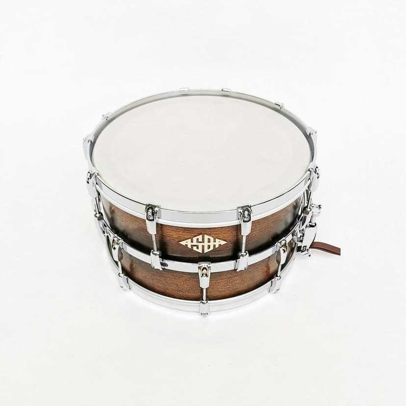 Wooden snare drum with polished silver lugs and a white drumhead positioned against a bright studio background.