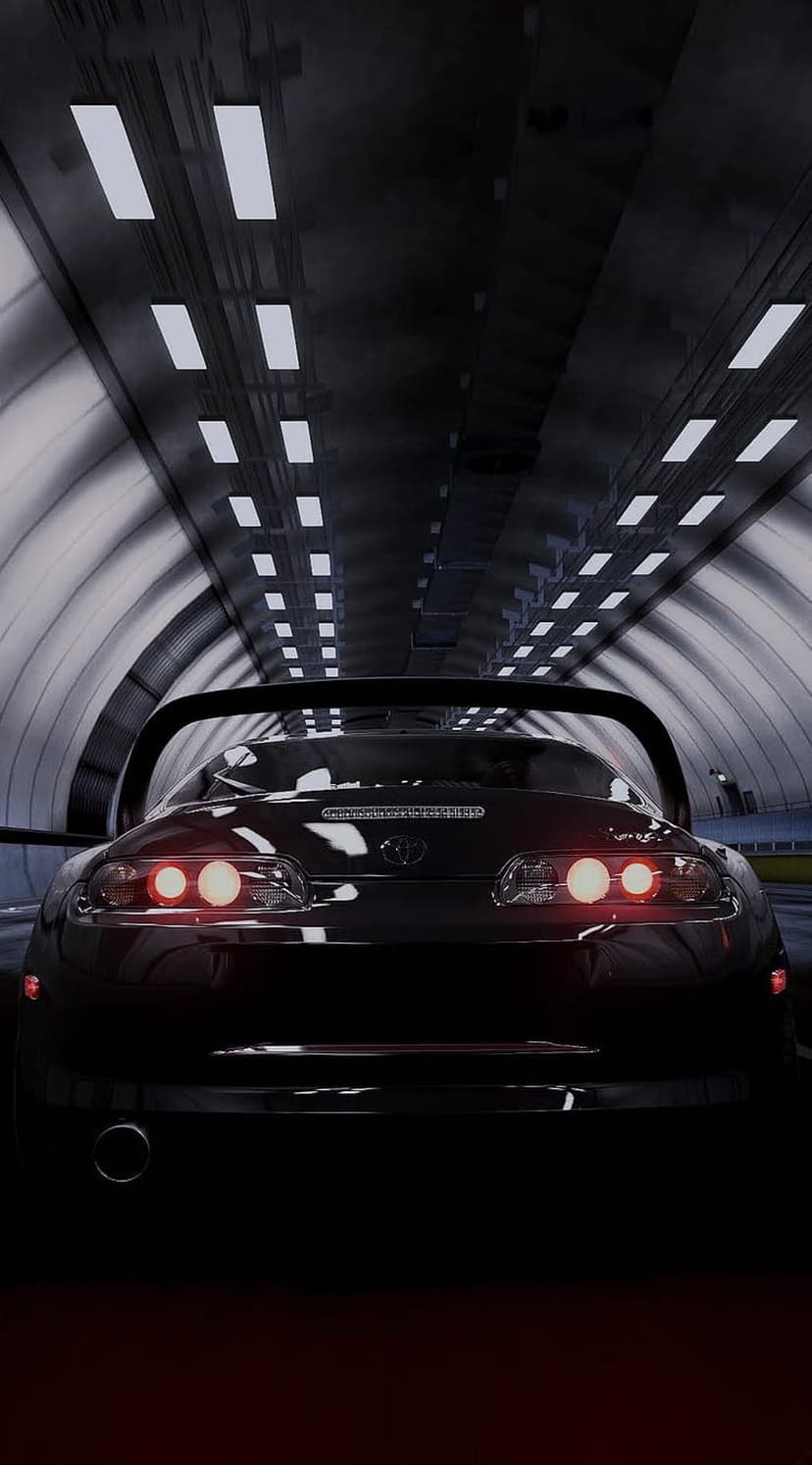 Black sports car with glowing red brake lights parked in a dark tunnel illuminated by linear white LED ceiling lights.