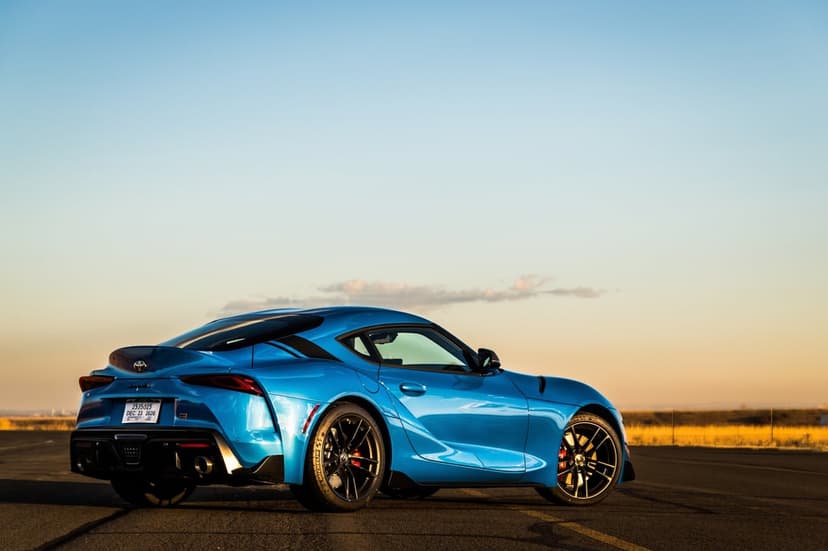 Blue Toyota Supra sports car parked on an open road at sunset with a wide clear sky in the background.