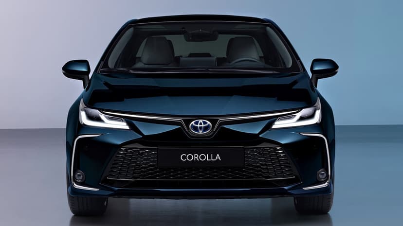 Front view of a dark blue Toyota Corolla with glowing LED headlights and a black honeycomb grille.