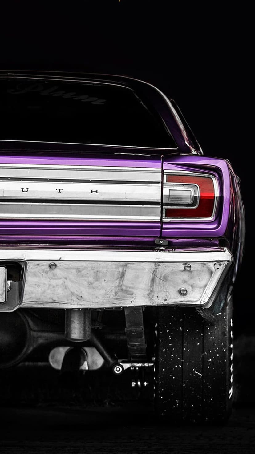 Purple Plymouth Barracuda rear bumper and tail lights featuring chrome badging and a dusty wide racing tire.