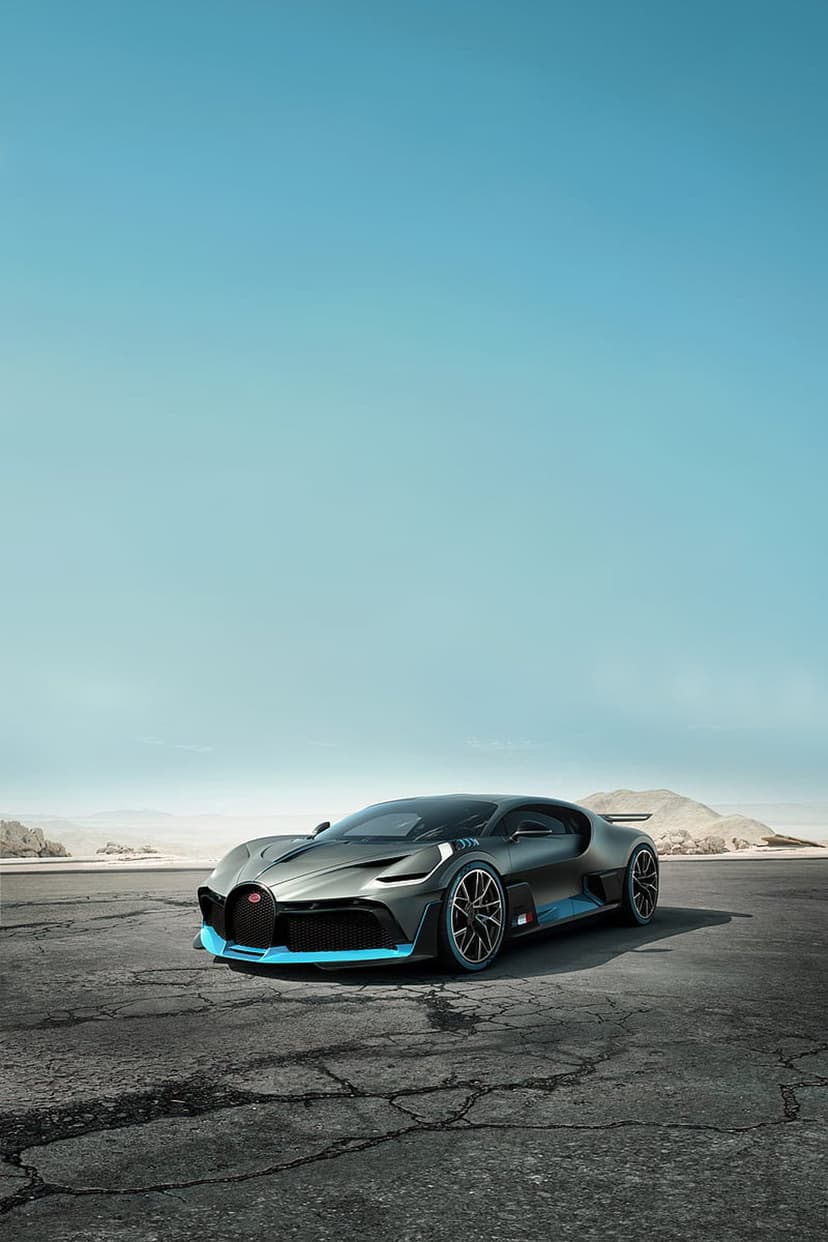 Bugatti Divo hypercar with blue trim stands on cracked desert pavement beneath a clear sky with distant mountains.